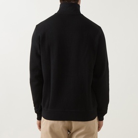 Model wearing Lacoste Half Zip Sweat in black, shown from the back, styled with beige trousers.