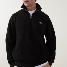 Model wearing Lacoste Half Zip Sweat in black, featuring silver half-zip and signature crocodile logo, styled over a white crew neck tee.