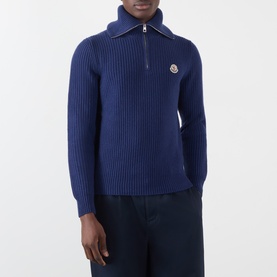 Model wearing Moncler navy wool half-zip ribbed knit sweater with logo badge, styled with dark trousers.
