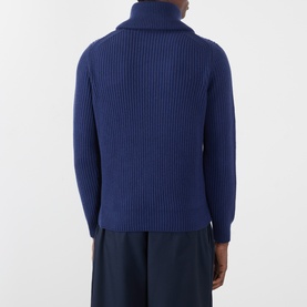 Model wearing Moncler navy wool half-zip jumper, shown from behind, with ribbed knit texture and roll neck detail.