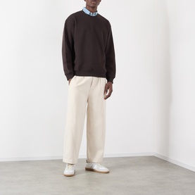 Model wearing NN07 Dusky Port cotton sweatshirt with cream wide-leg trousers, blue shirt collar visible, styled with white trainers.