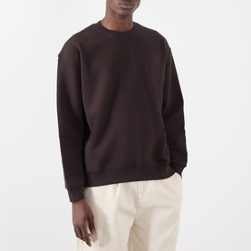 Model wearing NN07 Dusky Port cotton sweatshirt with crew neck and ribbed cuffs, styled with cream trousers.