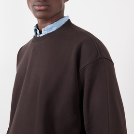 Model wearing NN07 Dusky Port cotton sweatshirt with crew neck, styled over a light blue collared shirt.