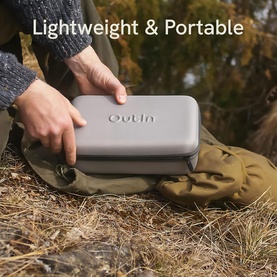 OutIn Nano Portable Espresso Machine Forest Green Bundle in compact grey carry case, held outdoors over a bag on rocky ground