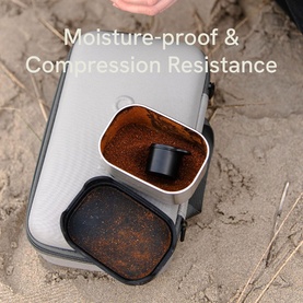 OutIn Nano Portable Espresso Machine Forest Green Bundle with open coffee pod compartment, shown outdoors highlighting moisture-proof construction