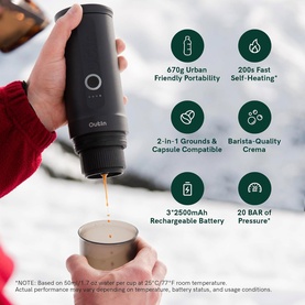 OutIn Nano Portable Espresso Machine in Forest Green, held outdoors in snowy setting, brewing espresso into a metal cup