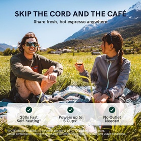OutIn Nano Portable Espresso Machine in Forest Green used outdoors by two people sitting on grass with mountain views