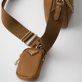 Prada Accessories brown nylon mini pouch with gold-tone triangle logo, zip closure, and wide woven shoulder strap with chain detail.
