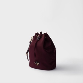 Burgundy canvas bucket bag with gold-tone hardware, drawstring closure, and adjustable shoulder strap