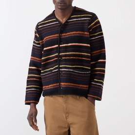 Model wearing Sacai Black Multi striped wool cardigan with V-neck and button front, styled with tan trousers.