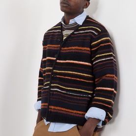 Model wearing SACAI Black Multi striped wool cardigan with button front, styled over a light blue shirt with tan trousers