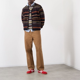 Model wearing SACAI Black Multi striped wool cardigan, styled with tan trousers, striped jumper, and red trainers.