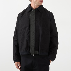 Model wearing Sacai Reversible Bomber Jacket in black, showing point collar, front zip with button placket and contrast trim detailing.
