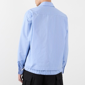 Model wearing SACAI light blue stripe cotton casual shirt, shown from rear, with black trousers visible at hem