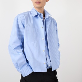 Model wearing SACAI light blue stripe cotton casual shirt with white button placket and spread collar, styled with black trousers