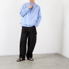 Model wearing Sacai black cotton-nylon casual trousers with wide-leg fit, styled with a light blue jacket and black sandals.
