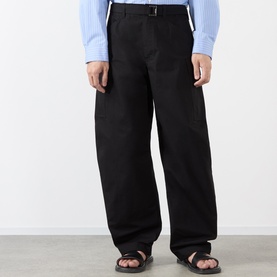 Model wearing Sacai black cotton-nylon casual trousers with wide leg fit and buckle waistband detail, styled with blue knit and sandals