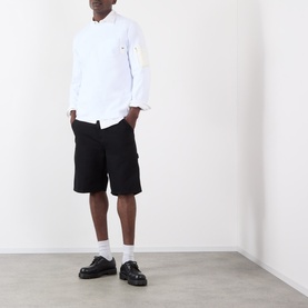 Model wearing SACAI white cotton long-sleeve shirt with black cargo shorts, white socks and black chunky loafers.