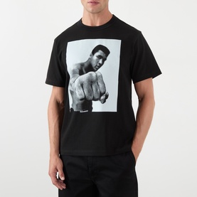 Model wearing Sacai black cotton T-shirt featuring a large monochrome Muhammad Ali graphic print to the chest.