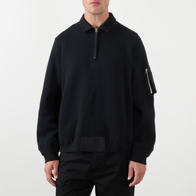 Model wearing SACAI black cotton-blend polo sweatshirt with half-zip collar, nylon sleeve pocket, and utility tab hem detail