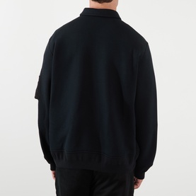 Model wearing Sacai black cotton-blend polo sweatshirt, back view, with utility pocket detail on sleeve and collar neckline.