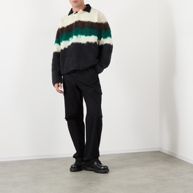 Model wearing Sacai Black Multi wool polo with tie-dye stripe detail in cream, brown and green, styled with black cargo trousers and chunky boots.