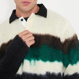 Model wearing SACAI Black Multi wool polo with contrast stripe knit in cream, brown and green, black collar detail visible.