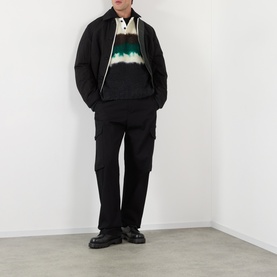 Model wearing Sacai Black Multi wool polo with tie-dye panel, styled with black cargo trousers and chunky loafers