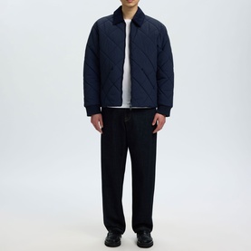 Model wearing Selected Bryce Quilted Jacket in Sky Captain navy, styled with black wide-leg trousers and black shoes