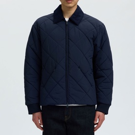 Model wearing Selected Bryce Quilted Jacket in Sky Captain, featuring diamond quilting, spread collar, two-way zip, styled with dark jeans