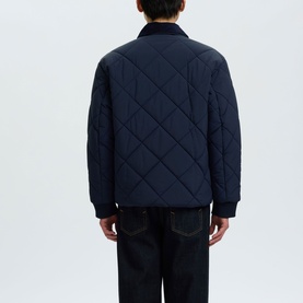 Model wearing Selected Bryce Quilted Jacket in Sky Captain, back view showing diamond quilting, ribbed cuffs, paired with dark jeans