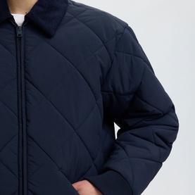 Model wearing Selected Bryce Quilted Jacket in Sky Captain, showing diamond quilting detail and zip fastening at chest