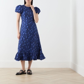 Model wearing Sister Jane navy floral midi dress with puff sleeves and ruffle hem, styled with black patent loafers