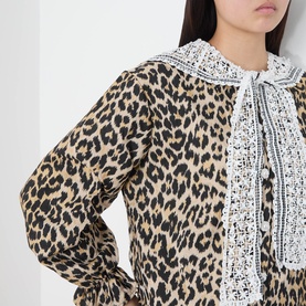 Model wearing Sister Jane dress in multi leopard print with white lace collar and tie neck detail.