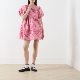 Model wearing Sister Jane pink floral jacquard mini dress with puff sleeves, styled with white socks and black mary jane shoes