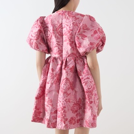 Model wearing Sister Jane pink floral jacquard mini dress with voluminous puff sleeves, cinched waist, and open back detail.