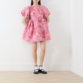 Model wearing Sister Jane pink floral jacquard mini dress with puff sleeves, styled with black Mary Jane shoes and white socks