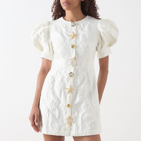 Model wearing Sister Jane Milos Brooches Mini Dress in white jacquard with puff sleeves and gold star embellished buttons