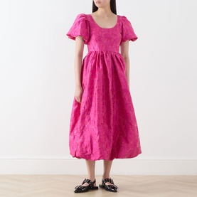 Model wearing Sister Jane pink jacquard midi dress with puff sleeves, scoop neck, and full skirt, styled with black loafer mules