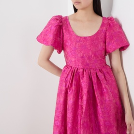 Model wearing Sister Jane pink jacquard dress with puff sleeves, scoop neckline, and full gathered skirt