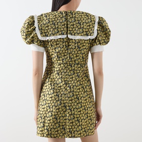 Model wearing Sister Jane Olive Dress, rear view, featuring puff sleeves, floral jacquard, and white sailor collar trim