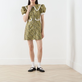 Model wearing Sister Jane olive floral mini dress with puff sleeves and white lace collar trim, styled with white socks and black mary jane shoes