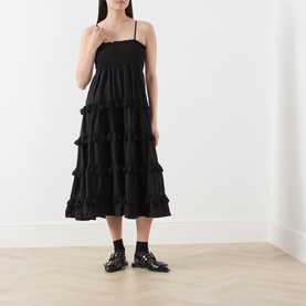 Model wearing Sister Jane Sandstone Tassel Tiered Dress in black, midi length with tiered ruffled skirt and cami straps, styled with black loafers