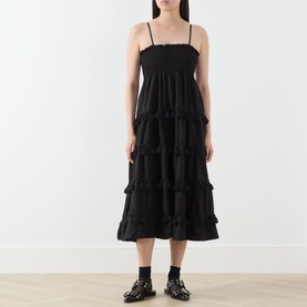 Model wearing Sister Jane Sandstone Tassel Tiered Dress in black, with shirred bodice, tassel-trimmed tiers, styled with black loafers