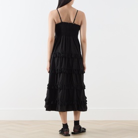 Model wearing Sister Jane Sandstone Tassel Tiered Dress in black, showing tiered midi skirt, cami straps and shirred bodice, back view