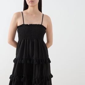 Model wearing Sister Jane Sandstone Tassel Tiered Dress in black, featuring shirred bodice, adjustable cami straps and tiered ruffled skirt