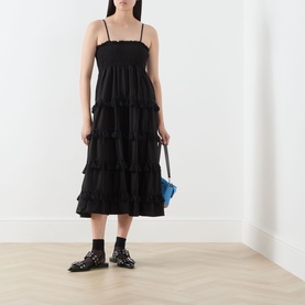 Model wearing Sister Jane Sandstone Tassel Tiered Dress in black, midi length with tiered skirt and cami straps, styled with blue bag and black