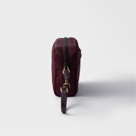 Prada Accessories burgundy nylon crossbody bag, side profile view, gold-tone hardware and detachable strap clip visible