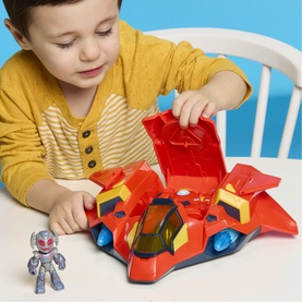 Child playing with Superheroes multicoloured jet playset with opening cockpit and small superhero figure on a white table.
