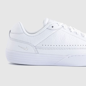 Nike trainer in white tumbled leather with perforated detailing, tonal micro swoosh logo, and white flatform sole.